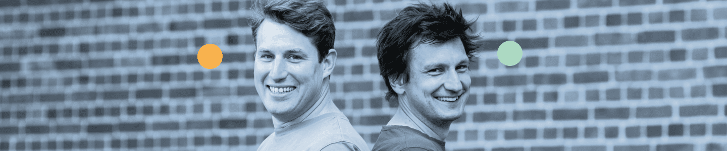 Die Gründer Friedo Scharf und Sebastian Trapp stehen Rücken an Rücken und lächeln in die Kamera.